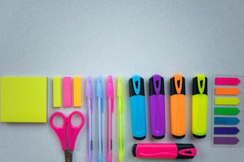 a group of office supplies sitting on top of a table, ((neon colors)), box cutter, neon highlights, multicolor