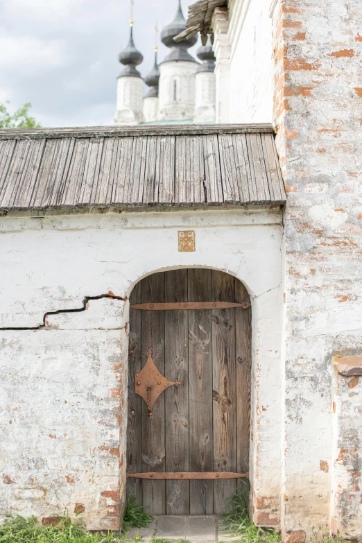 an old brick building with a wooden door, an album cover, inspired by Isaac Levitan, unsplash, renaissance, white, churches, low quality photo, old ruins
