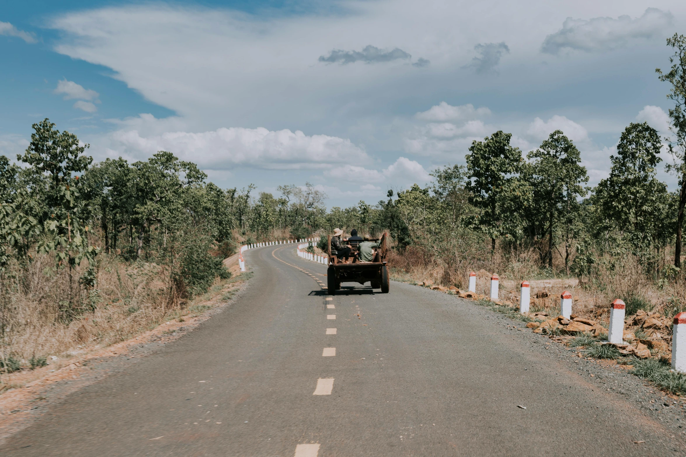 a truck driving down a road next to a forest, an album cover, pexels contest winner, angkor thon, thumbnail, india, maintenance photo