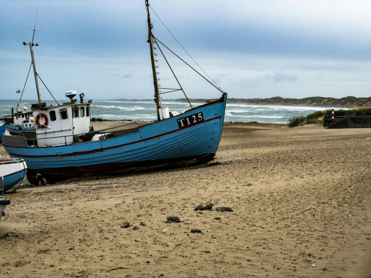 a blue boat sitting on top of a sandy beach, a photo, inspired by Hendrik Willem Mesdag, pexels contest winner, stormy seas, slide show, a wooden, rugged