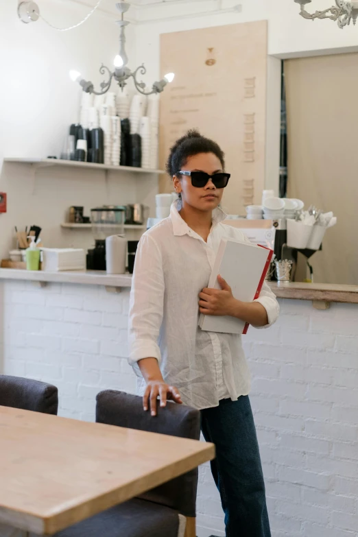 a man that is standing in front of a table, wearing sunglasses, tessa thompson, wearing a white button up shirt, walking to the right