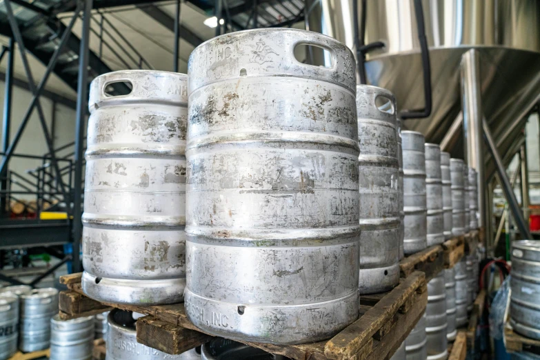 a bunch of kegs sitting on top of a wooden pallet, profile image, steel plating, thumbnail, large jars on shelves