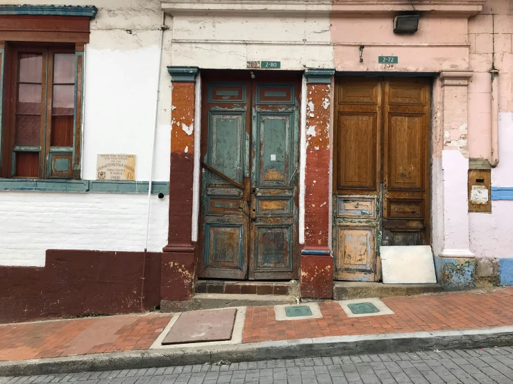 a couple of doors that are on the side of a building, an album cover, unsplash, quito school, old shops, old furniture, built on a steep hill, 1990's photo