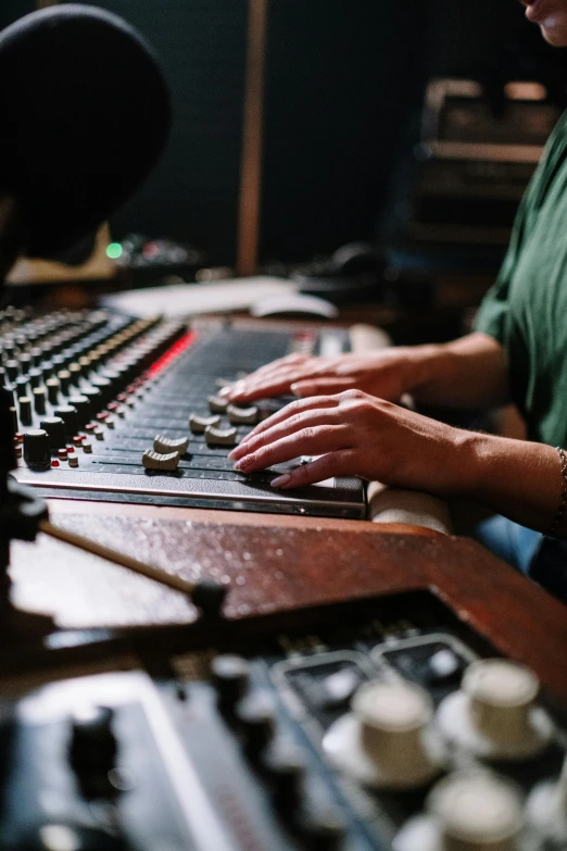 a man sitting in front of a mixing desk, by Everett Warner, pexels, carefully crafted, beth harmon, hands, album cover