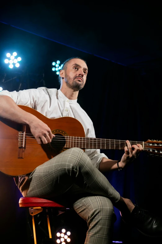 a man sitting on a stool playing a guitar, antipodeans, edin durmisevic, headshot, square, ted nasmit