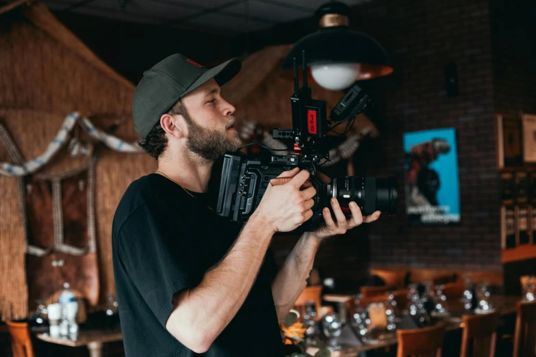 a man holding a camera in a restaurant, red cinema camera, avatar image