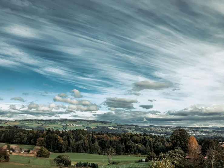 a couple of sheep standing on top of a lush green field, inspired by Thomas Struth, pexels contest winner, sky with swirling clouds, during autumn, overlooking a valley with trees, panorama