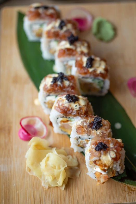 a wooden cutting board topped with sushi rolls, a picture, portrait n - 9, caramel, bumps, vine twist