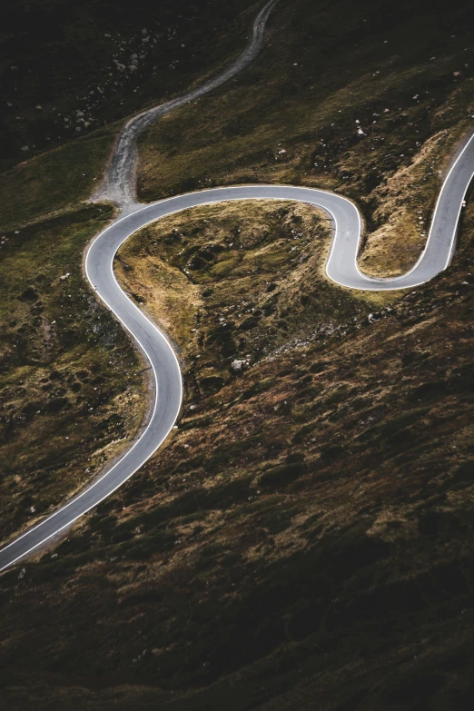 an aerial view of a winding mountain road, by Adam Szentpétery, unsplash contest winner, thumbnail, wales, curls, cardboard