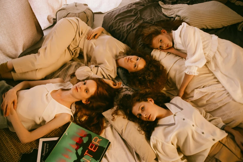 a group of women laying on top of a bed, an album cover, trending on pexels, ( redhead, valentin serov style, four hands, style of stranger things