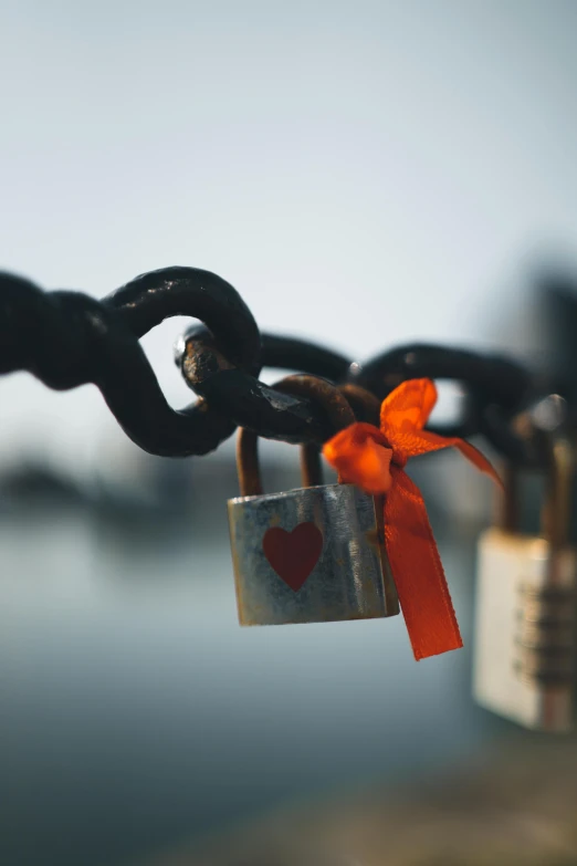 a couple of padlocks attached to a chain, a picture, pexels contest winner, orange ribbons, square, low-light, heartbreak