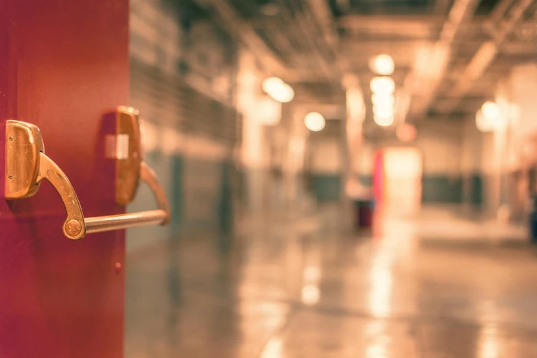 a close up of a door handle on a red door, pexels, happening, in school hallway, background blurred, 1 2 9 7, worksafe. instagram photo