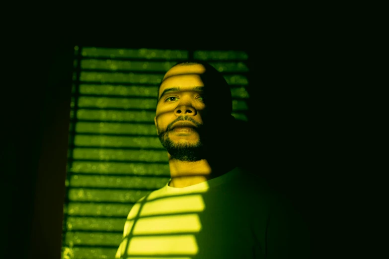 a man that is standing in front of a window, an album cover, by Pedro Pedraja, pexels, glowing green neon eyes, frank ocean, yellow light, profile picture 1024px