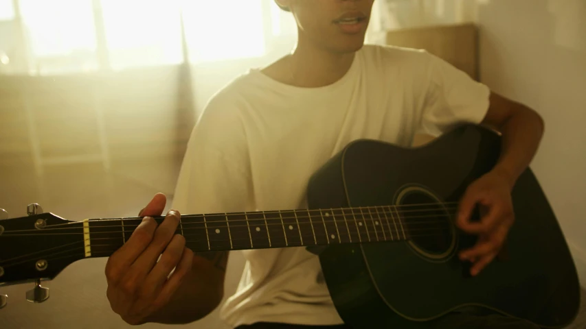 a close up of a person playing a guitar, by Gavin Hamilton, morning sunlight, taejune kim, light skin, lachlan bailey