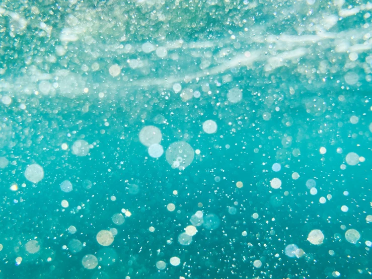 a close up of a body of water with bubbles, by Sophie Pemberton, light and space, teal energy, sparkles and glitter, sea foam, under water swimming