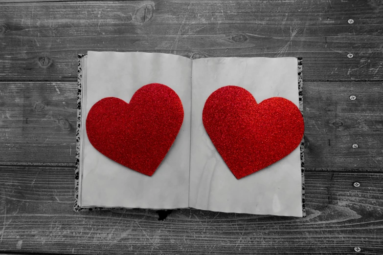 two red hearts sitting on top of an open book, an album cover, pixabay, multiple stories, fabric, sparkling, looking at each other mindlessly