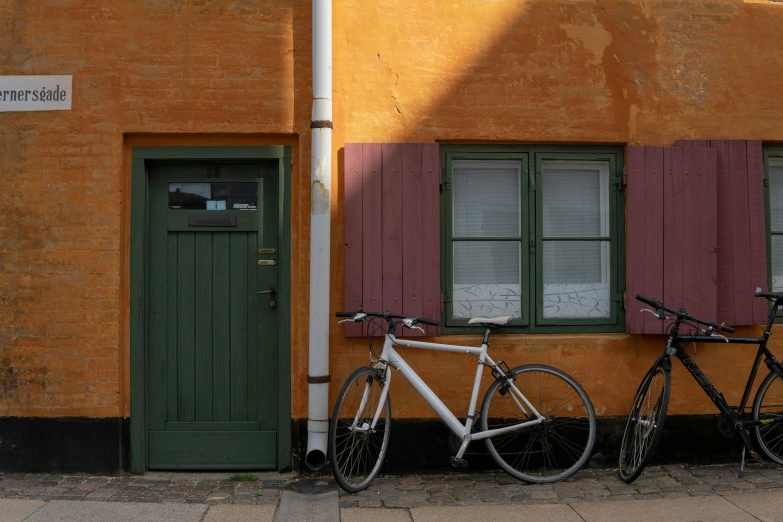 a couple of bikes parked next to a building, by Jesper Knudsen, pexels contest winner, earthy color scheme, swedish writing, 3 doors, profile image