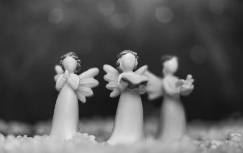 a black and white photo of three angel figurines, a black and white photo, by Marie Angel, pexels, bokeh!!!!, white wings, flower power, cute miniature resine figure