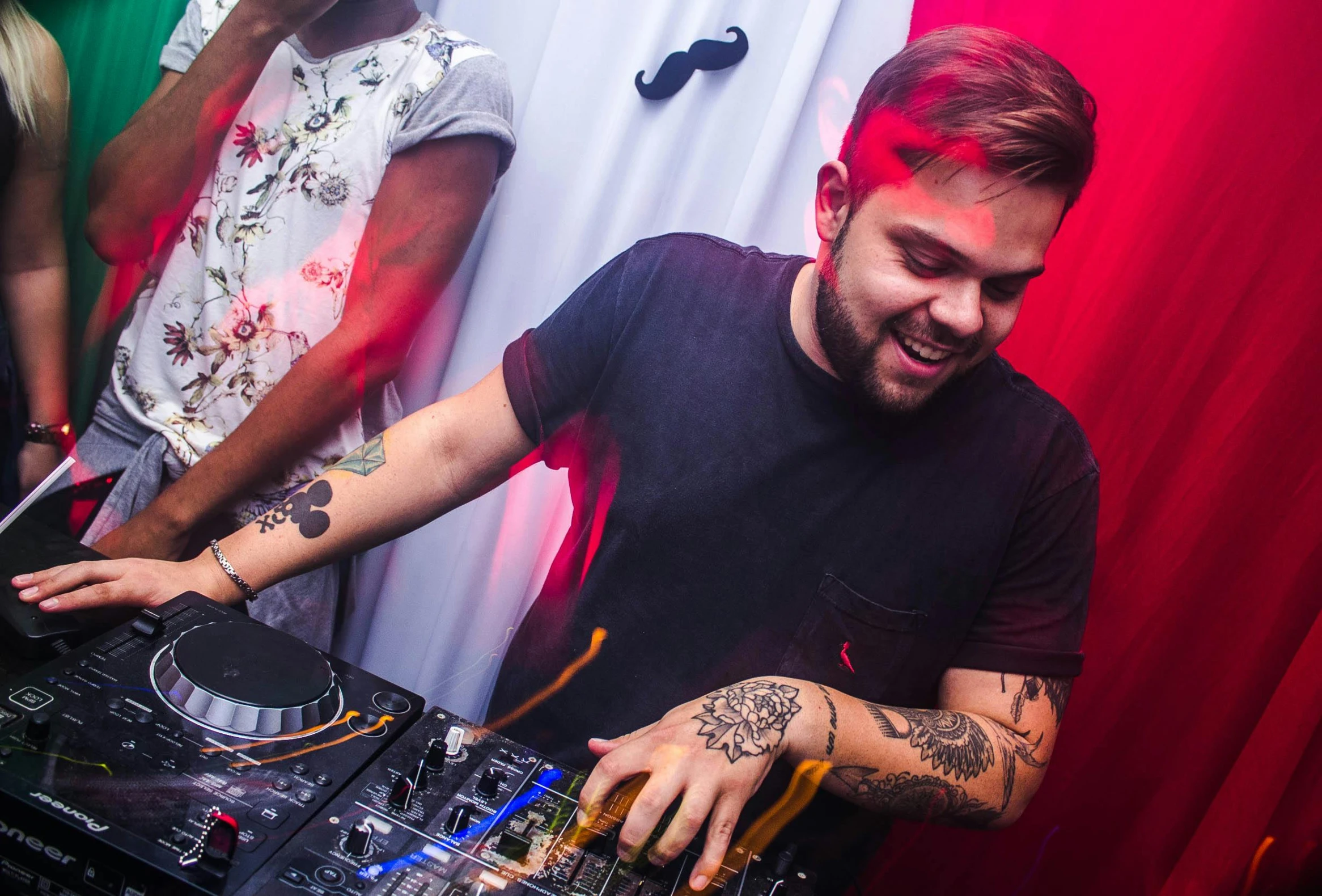 a man that is standing in front of a dj, liam, danilo torres, giddy smirk, party atmosphere