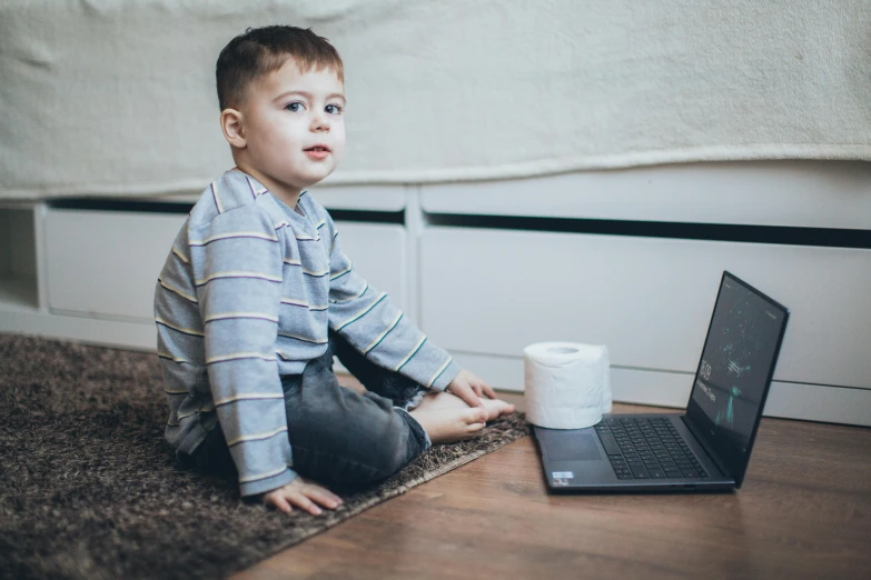 a little boy sitting on the floor next to a laptop, a portrait, by Adam Marczyński, pexels, siting on a toilet, avatar image, sitting across the room, promotional image