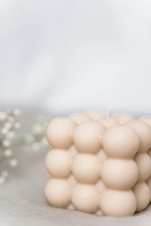 a close up of a candle on a table, soft geometric 3d shapes, bumps, beige mist, metaballs