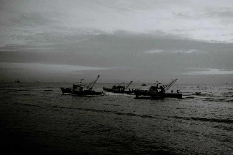 a couple of boats that are in the water, a black and white photo, pexels contest winner, hurufiyya, fishing boats, it's getting dark, dredged seabed, in formation