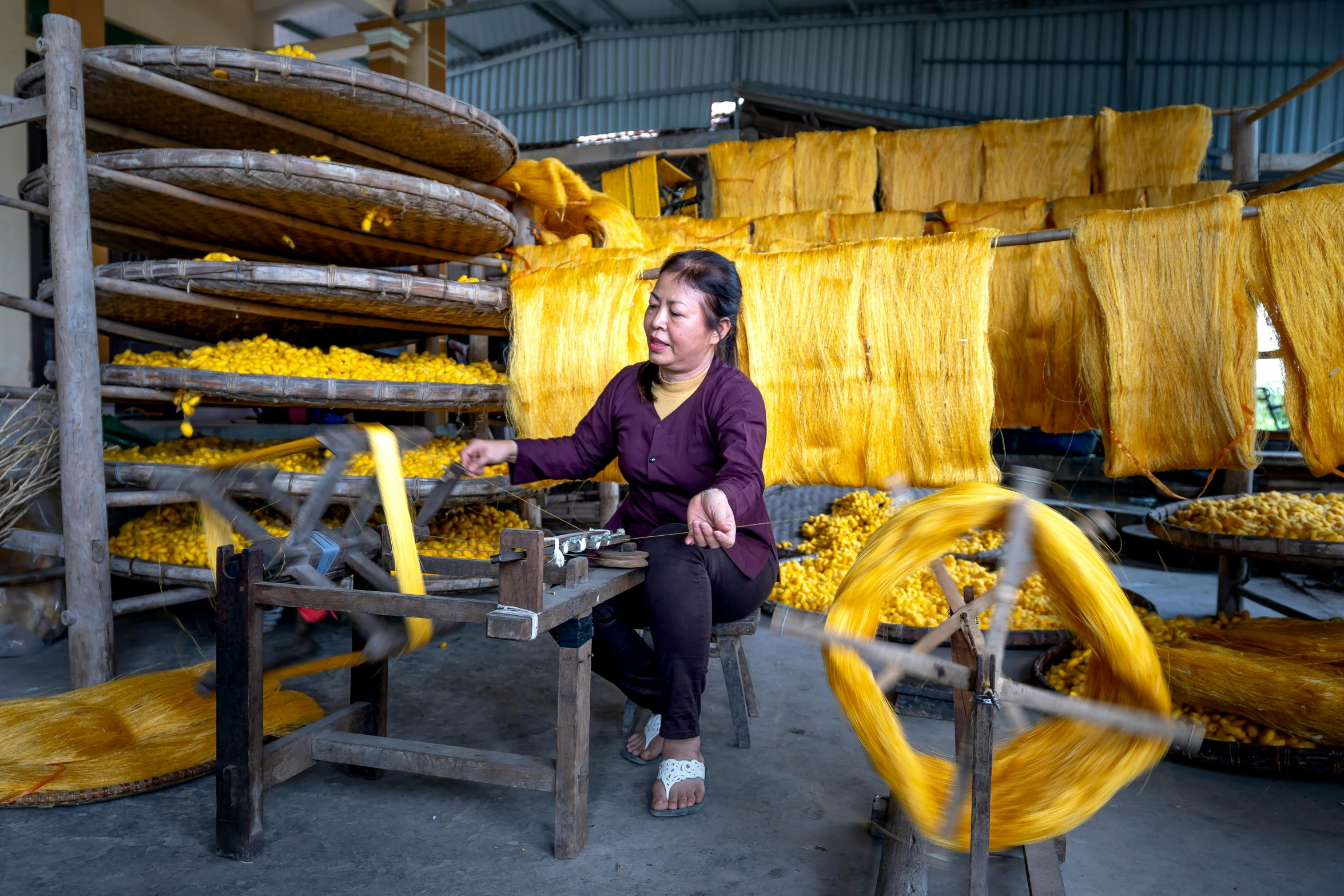 a woman sitting on a chair in a factory, inspired by Ruth Jên, gutai group, scarf made from spaghetti, sustainability, with yellow cloths, clothes made out of flower