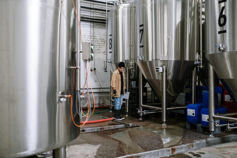 a man that is standing in front of some tanks, a photo, unsplash contest winner, process art, beer, stainless steel, ignant, brown