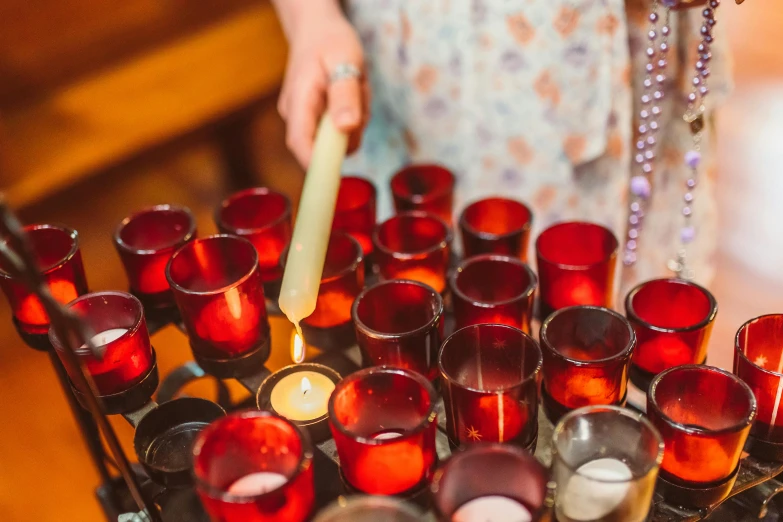 a close up of a person lighting a candle, by Anna Findlay, pexels, arts and crafts movement, red lanterns, amber glasses, mary in a sanctuary, wedding