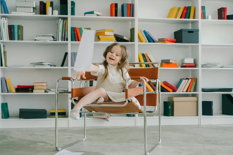 a little girl that is sitting in a chair, pexels contest winner, modernism, book shelf, office furniture, excited, brown and white color scheme