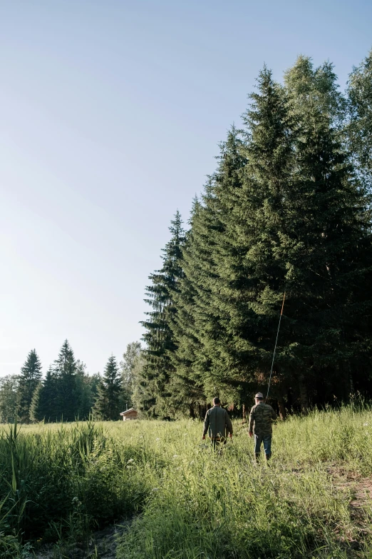 a group of people standing on top of a lush green field, spruce trees, fishing, woodland location, outdoor