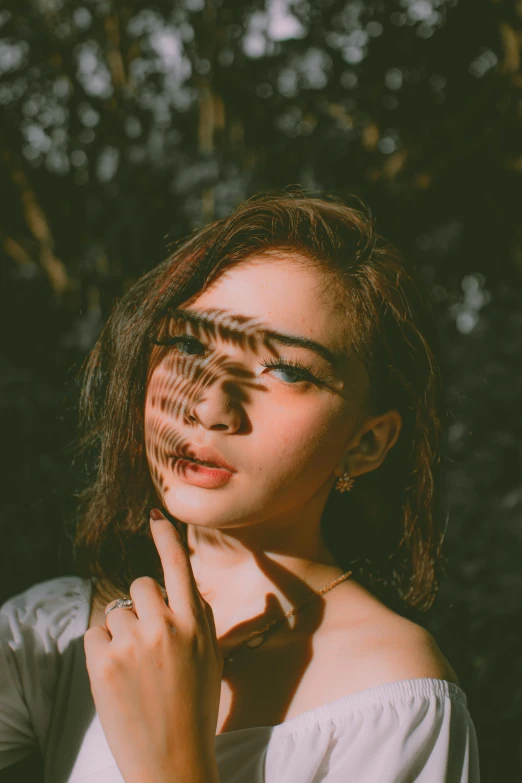 a woman with glasses standing in front of a tree, a picture, inspired by Elsa Bleda, trending on pexels, surrealism, stripe over eye, asian girl, faces covered in shadows, hand on cheek