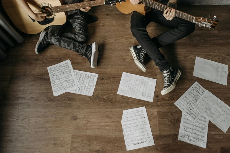 a couple of people sitting on top of a wooden floor, an album cover, by Julia Pishtar, pexels contest winner, piano guitar music notes key, 15081959 21121991 01012000 4k, studio floor, sheet music