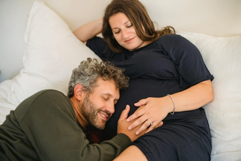a man and a woman laying on a bed, pexels contest winner, pregnant belly, looking off to the side, avatar image, profile image
