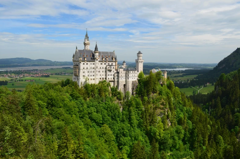 a castle sitting on top of a lush green hillside, by Daniel Lieske, pexels contest winner, art nouveau, white, german forest, tall spires, thumbnail