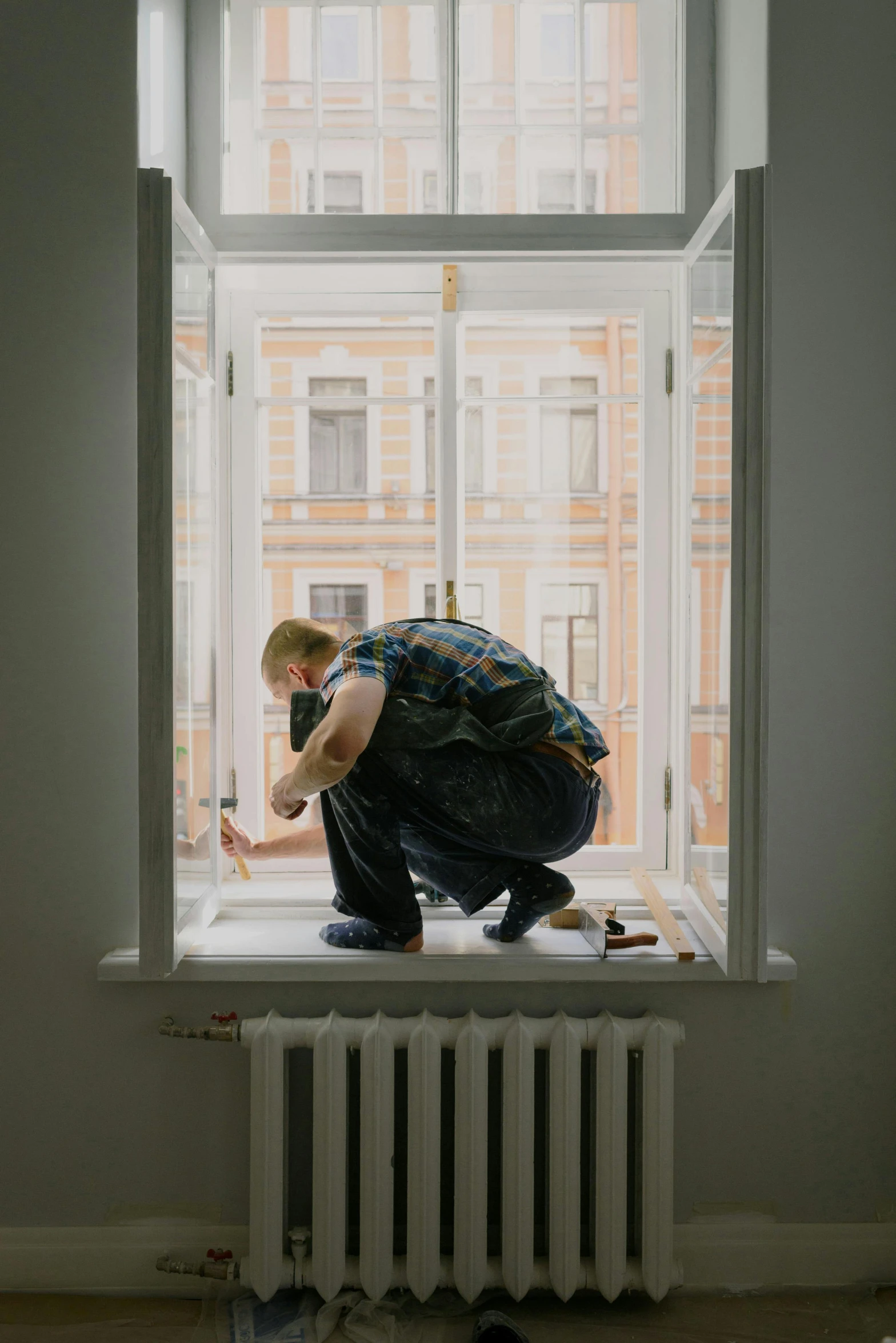 a man kneeling on top of a radiator in front of a window, by artist, pexels contest winner, hyperrealism, carpenter, fixing a leaking sink, knyazev konstantin, a blond