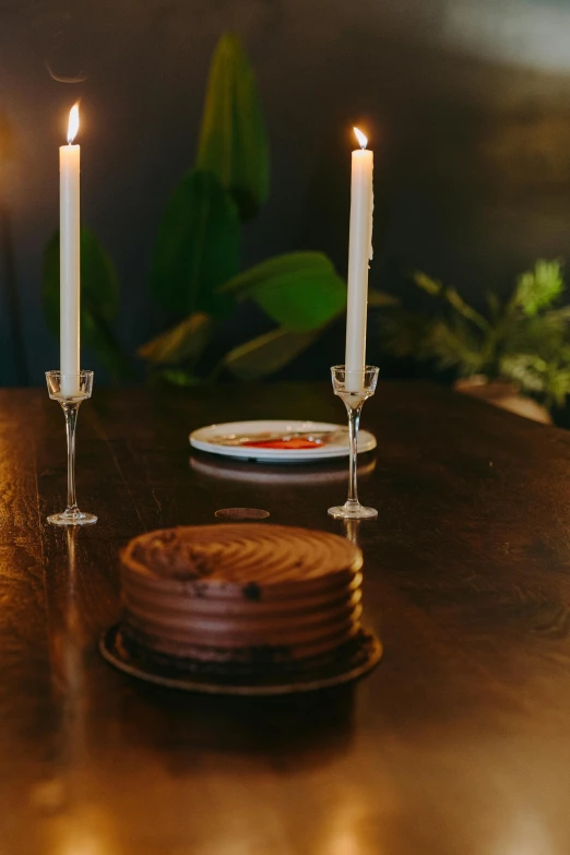 a couple of candles sitting on top of a wooden table, cake, offering a plate of food