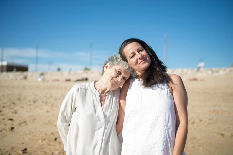 a couple of women standing on top of a sandy beach, a portrait, unsplash, dementia, portrait image