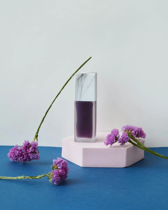 a vase filled with purple flowers on top of a blue table, inspired by Yves Klein, unsplash, minimalism, marble and wood and glass, lipstick, product view, silicone skin