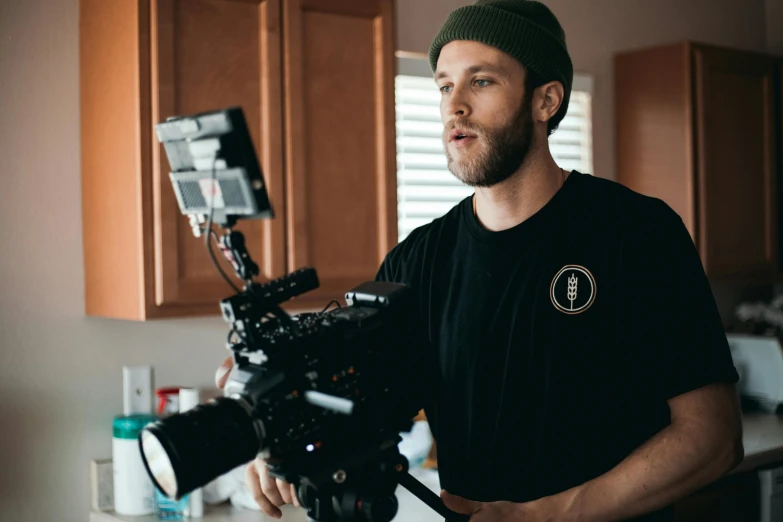 a man standing in a kitchen holding a camera, screenwriter, dustin lefevre, **cinematic, they share one head. cinematic