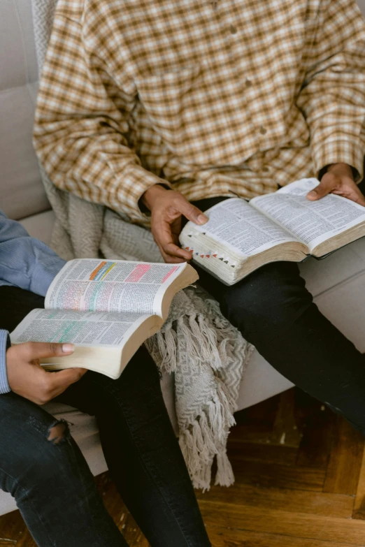 two people sitting on a couch reading books, by Carey Morris, trending on unsplash, holy themed, holding books, maintenance photo, lightly dressed