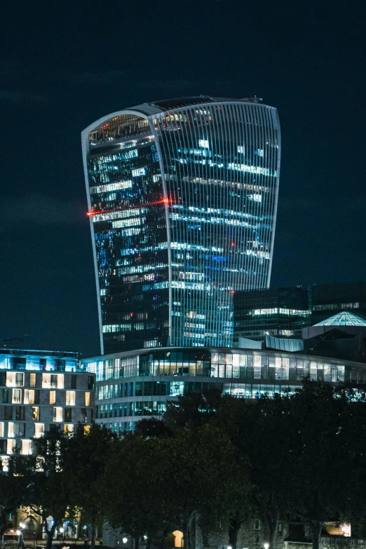 the city of london at night with the gherni building in the background, an album cover, 4k photo”, square, modern glass building, curvy build