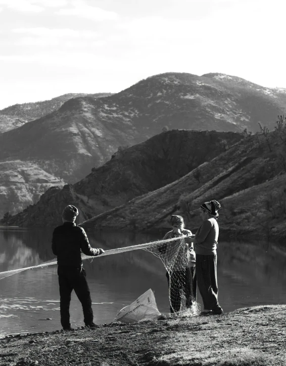 a group of men standing on top of a hill next to a lake, net of being, profile image, black an white, salmon