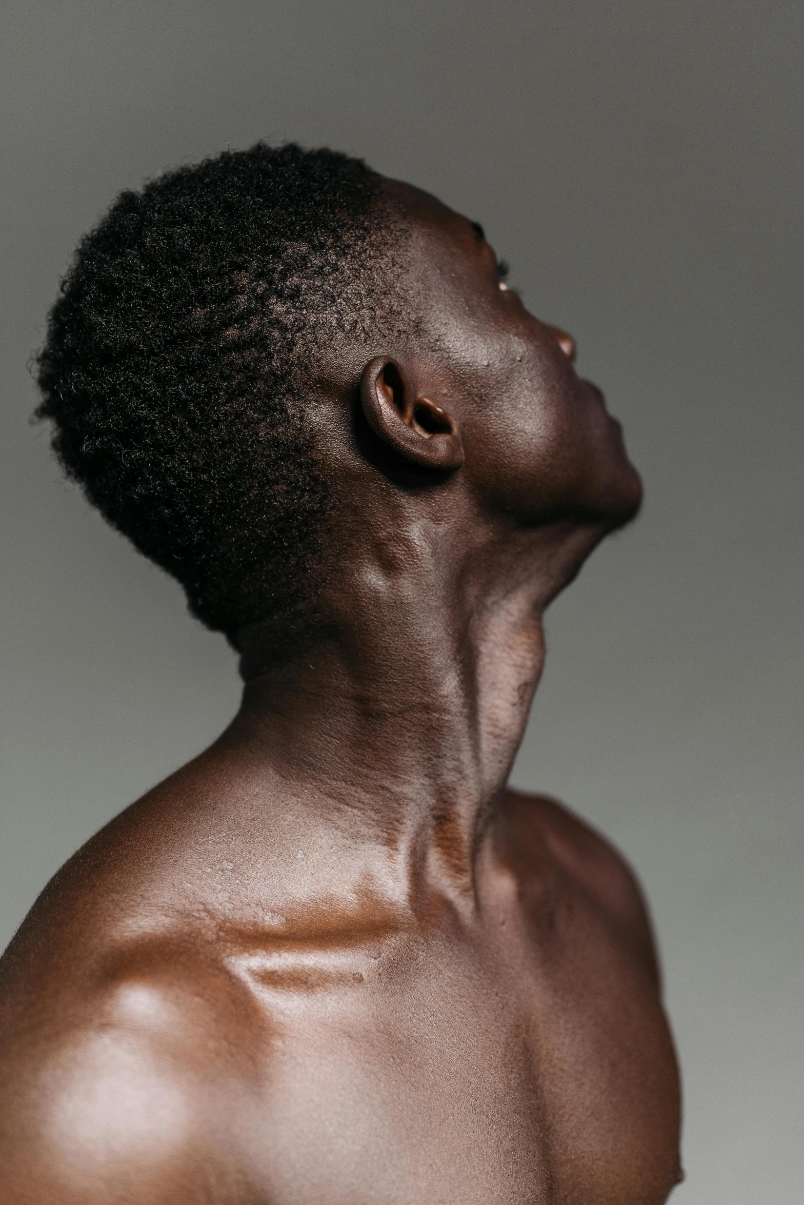 a close up of a man with no shirt on, an album cover, inspired by Robert Mapplethorpe, trending on pexels, hyperrealism, light-brown skin, profile pose, cybernetic neck implant, adut akech