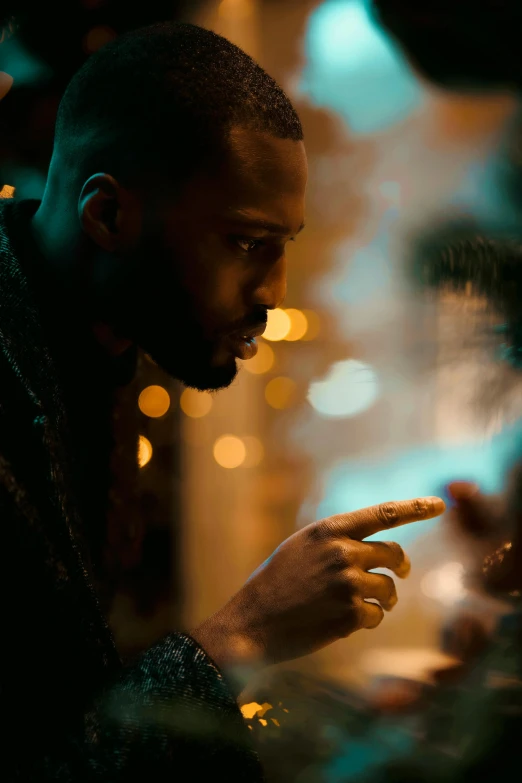 a man looking at his cell phone in the dark, an album cover, inspired by casey baugh, pexels contest winner, black man, flirting, pointing, bokeh effect