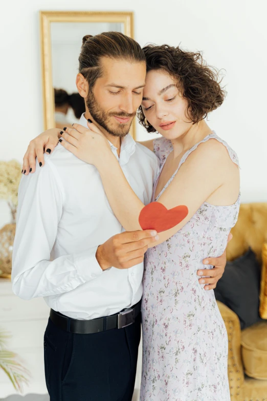 a man standing next to a woman holding a red heart, pexels contest winner, arm around her neck, ad image, at home, gif