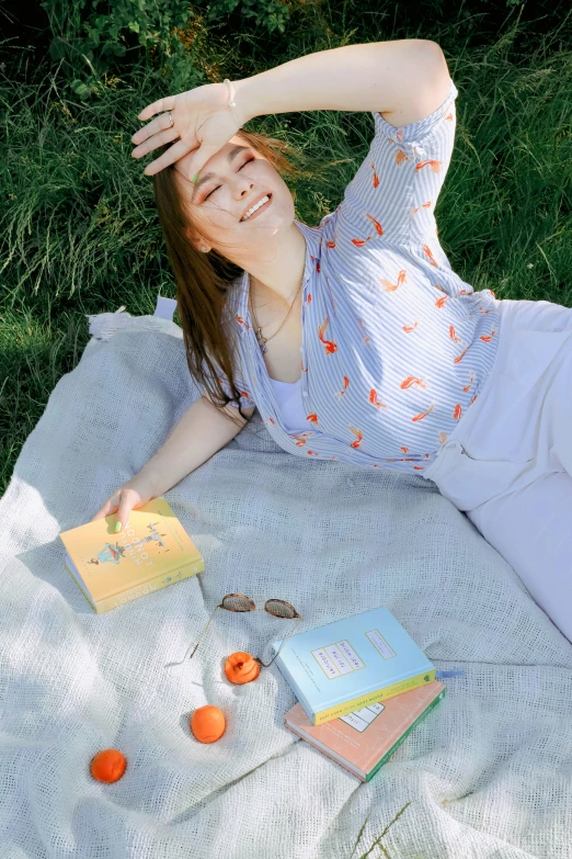 a woman laying on a blanket in the grass, holding books, orange and blue color scheme, throwing cards in the air, sydney sweeney