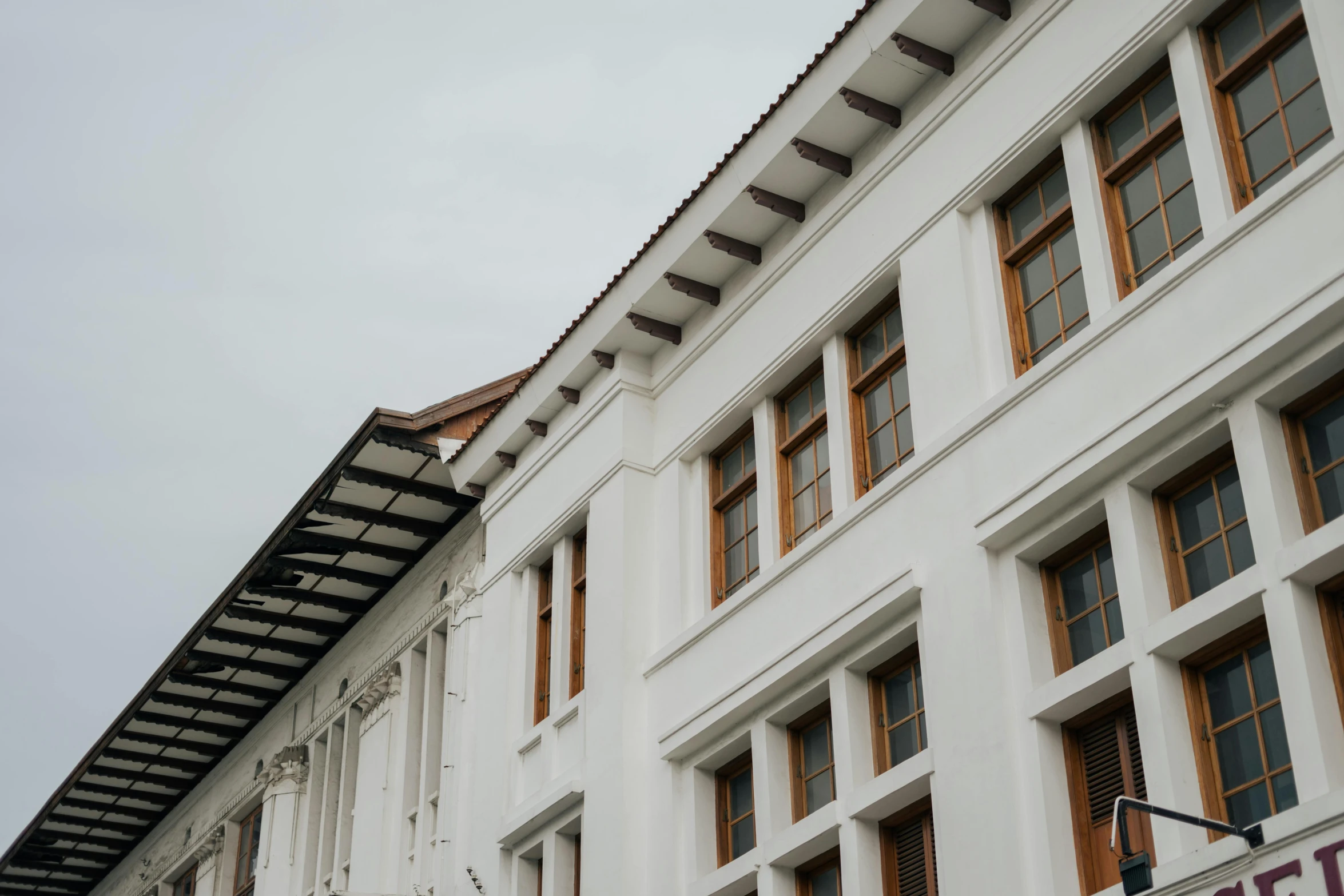 a sign that is on the side of a building, inspired by David Chipperfield, pexels contest winner, bengal school of art, white houses, colombo sri lankan city street, view from below, large open windows