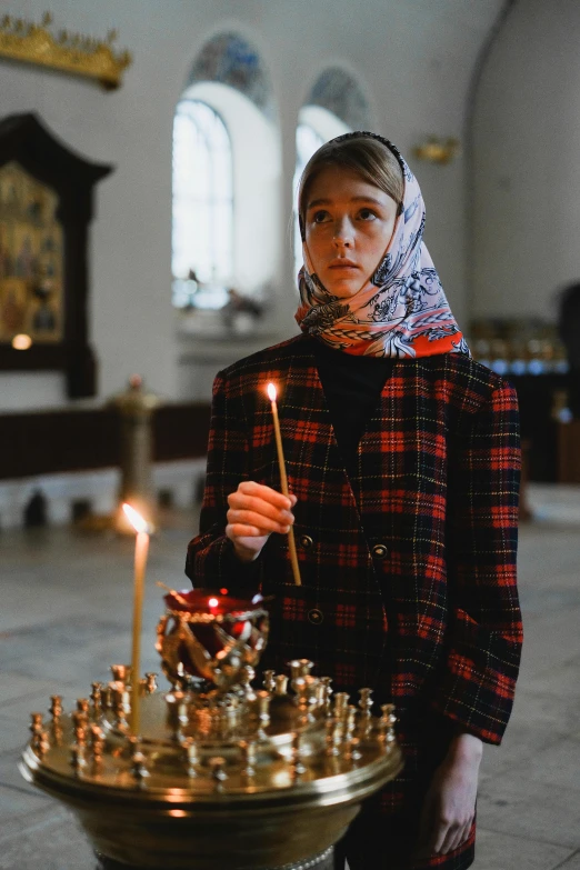 a woman holding a lit candle in a church, by Emma Andijewska, chess, wearing traditional garb, 2019 trending photo, school