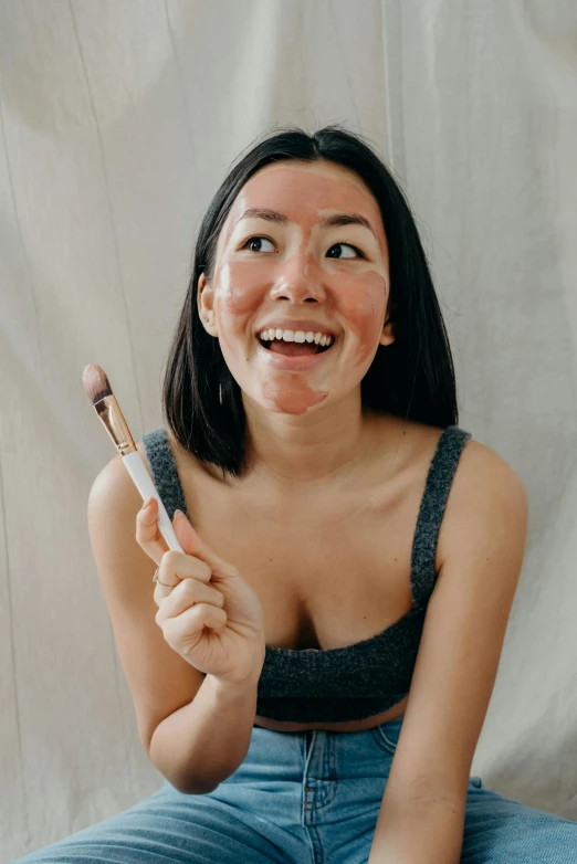 a woman sitting on the floor holding a toothbrush, by Julia Pishtar, trending on pexels, renaissance, burn scar left cheek, asian face, right - half a cheerful face, in professional makeup